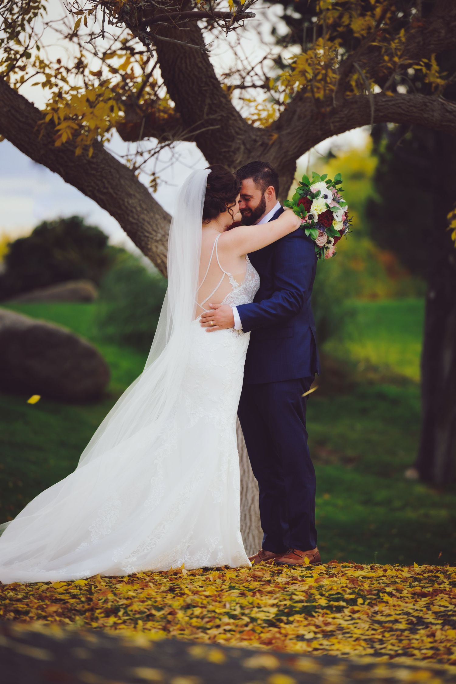 Married couple nuzzling each other under a tree