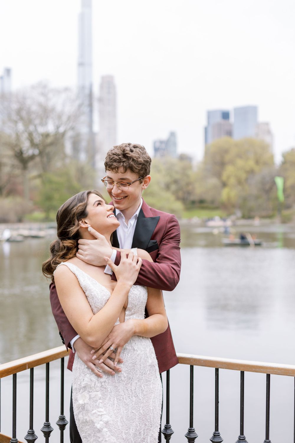 Romantic wedding portrait with New York City skyline and Central Park lake in background.