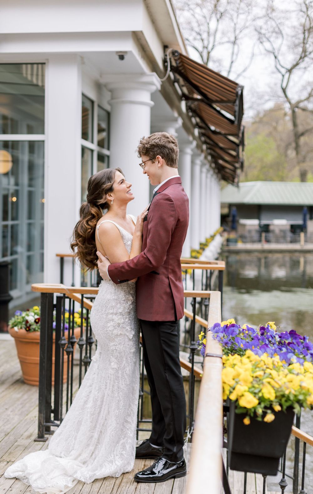Wedding couple embracing on a terrace with spring flowers and lake view.