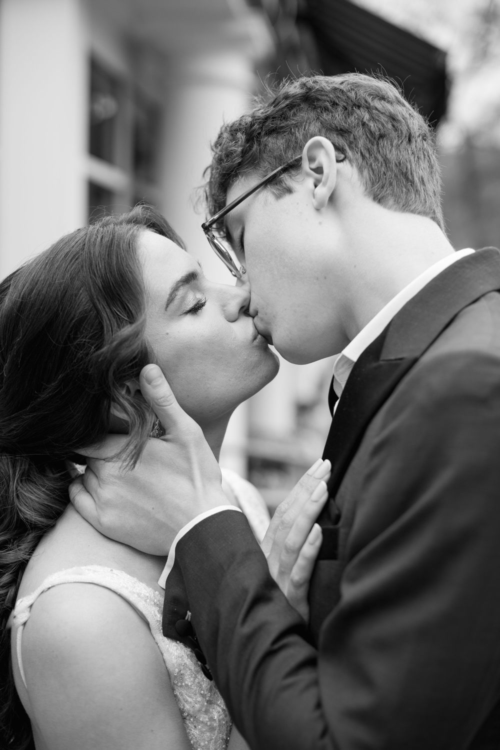 A romantic black and white wedding photo of a tender kiss between newlyweds.
