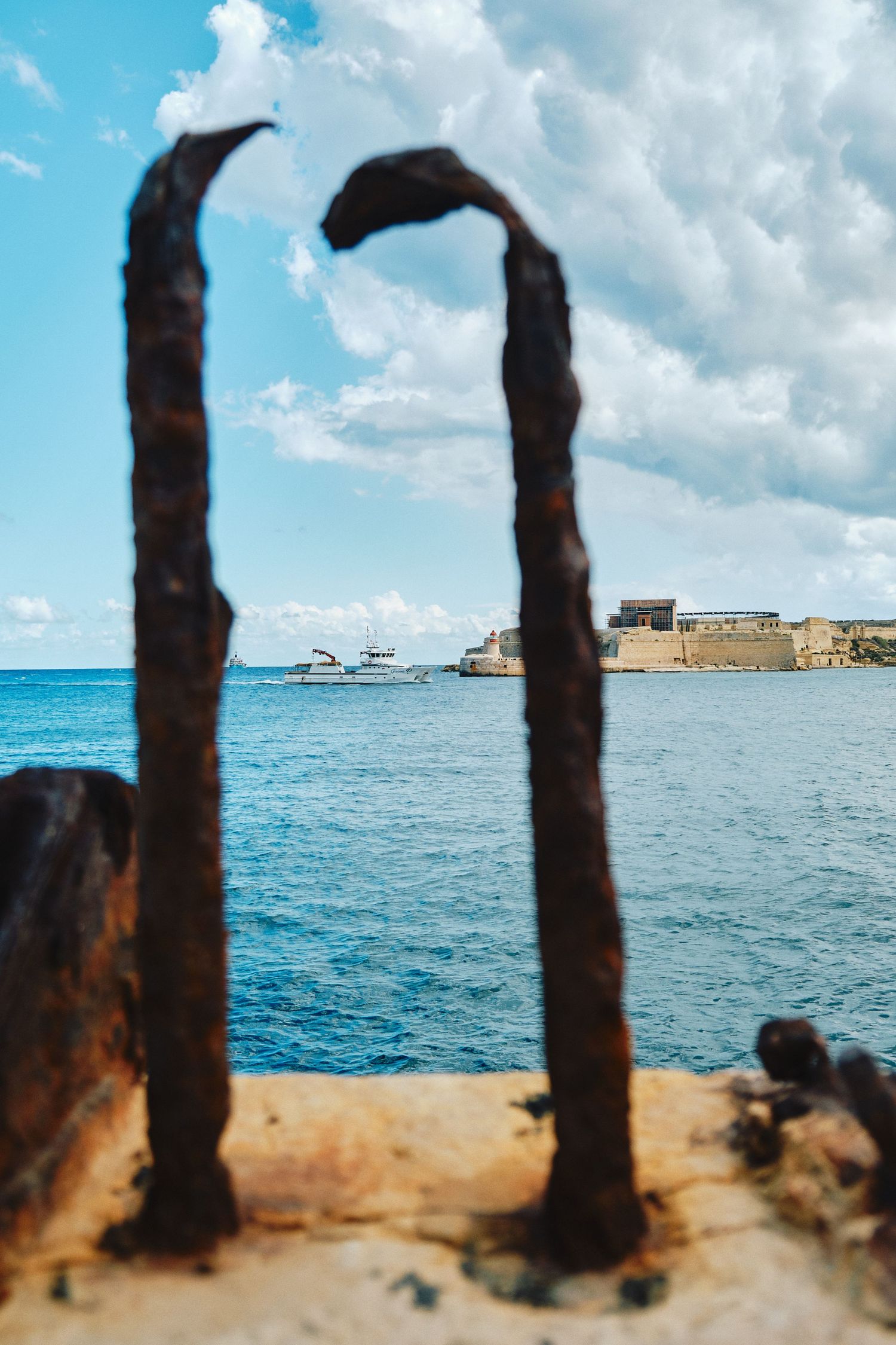 Historic archway frames a view of the Mediterranean Sea and ancient fortress in Malta.