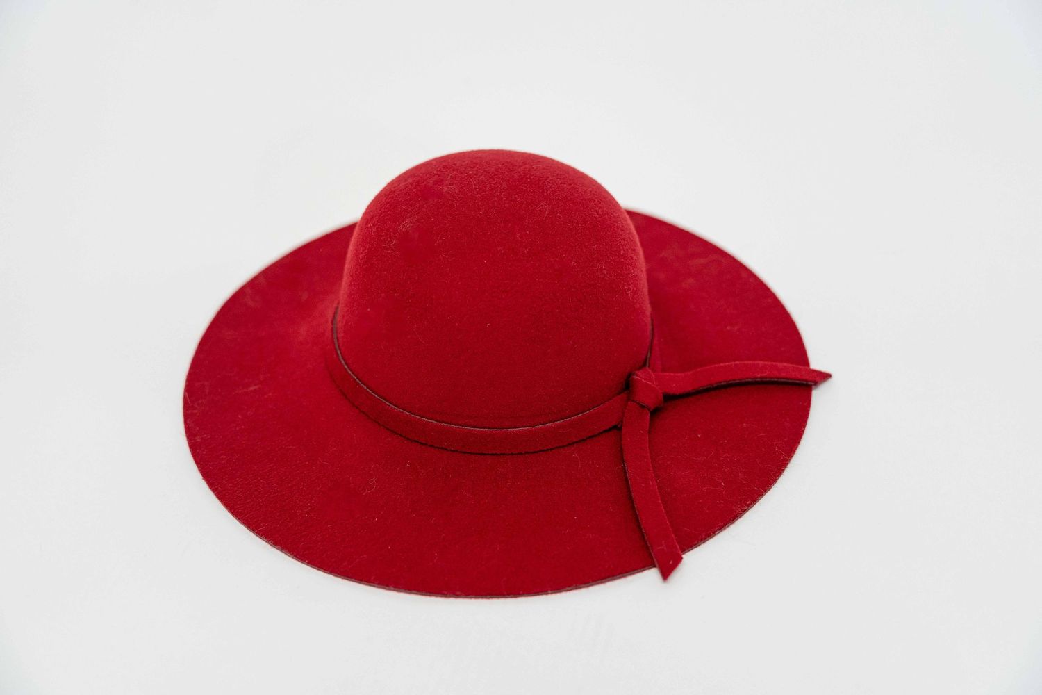 Elegant red wide-brim felt hat with matching ribbon band on white background.