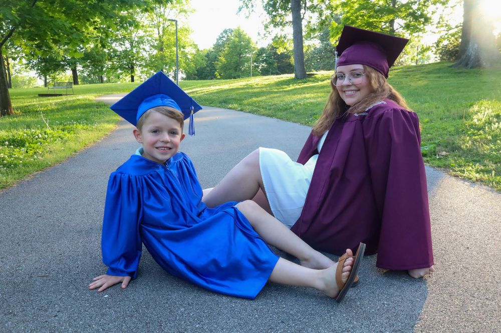 Graduation photo shoot with playful poses on outdoor pathway.