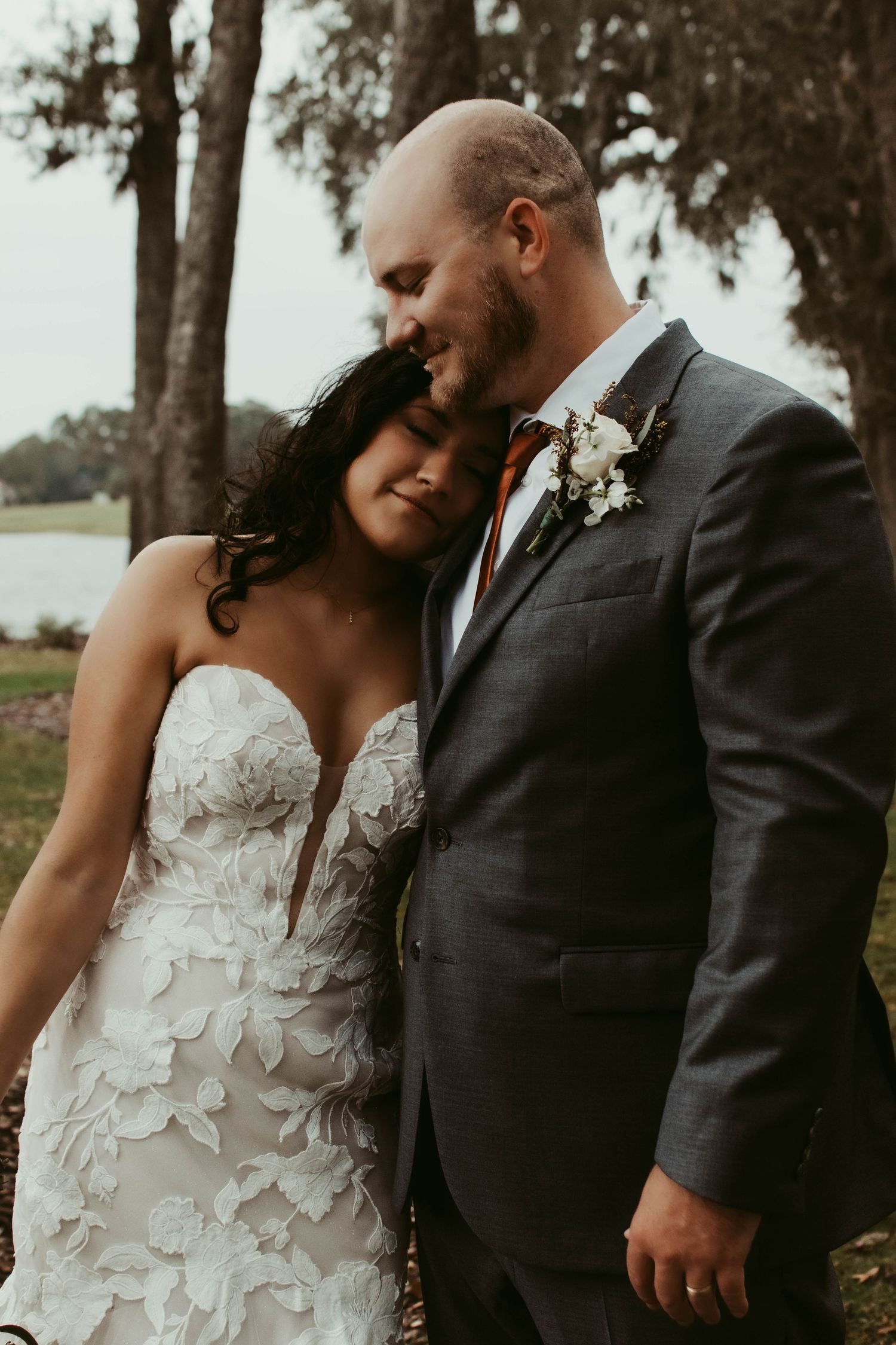 Intimate wedding couple portrait showing detailed floral lace dress and dark suit.