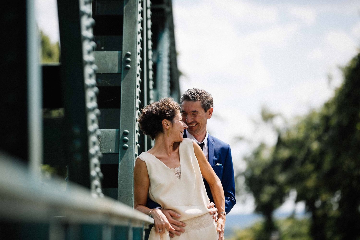 Couple sharing an intimate moment on a bridge with soft natural lighting.