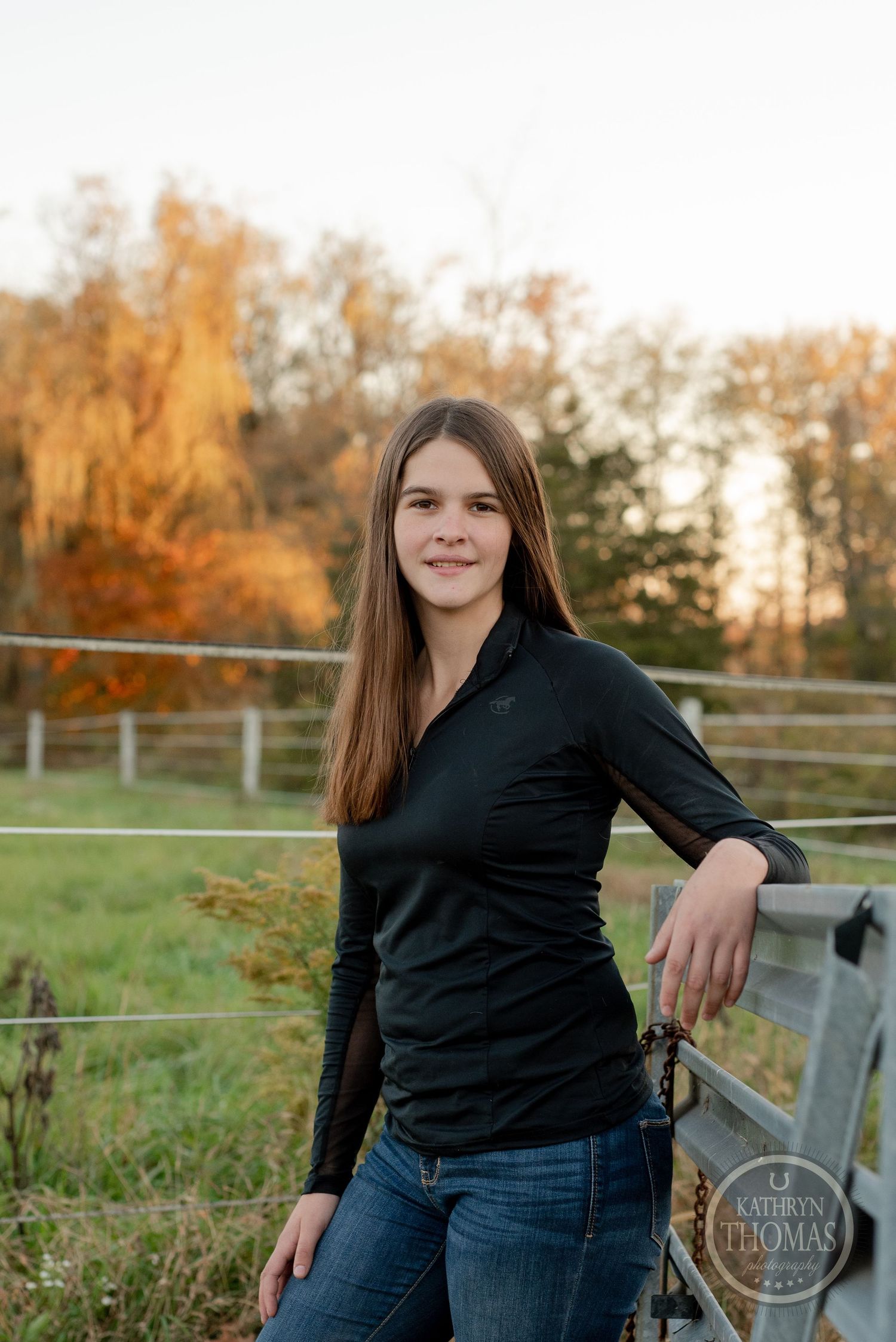 Portrait against metal fence with fall colors and pastoral background.