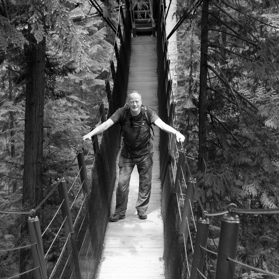 Tim Stewart, Wedding Photographer standing on a rope bridge in black and white.