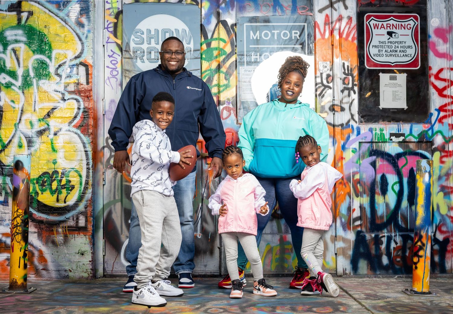 Family posing together against vibrant graffiti wall in urban setting.