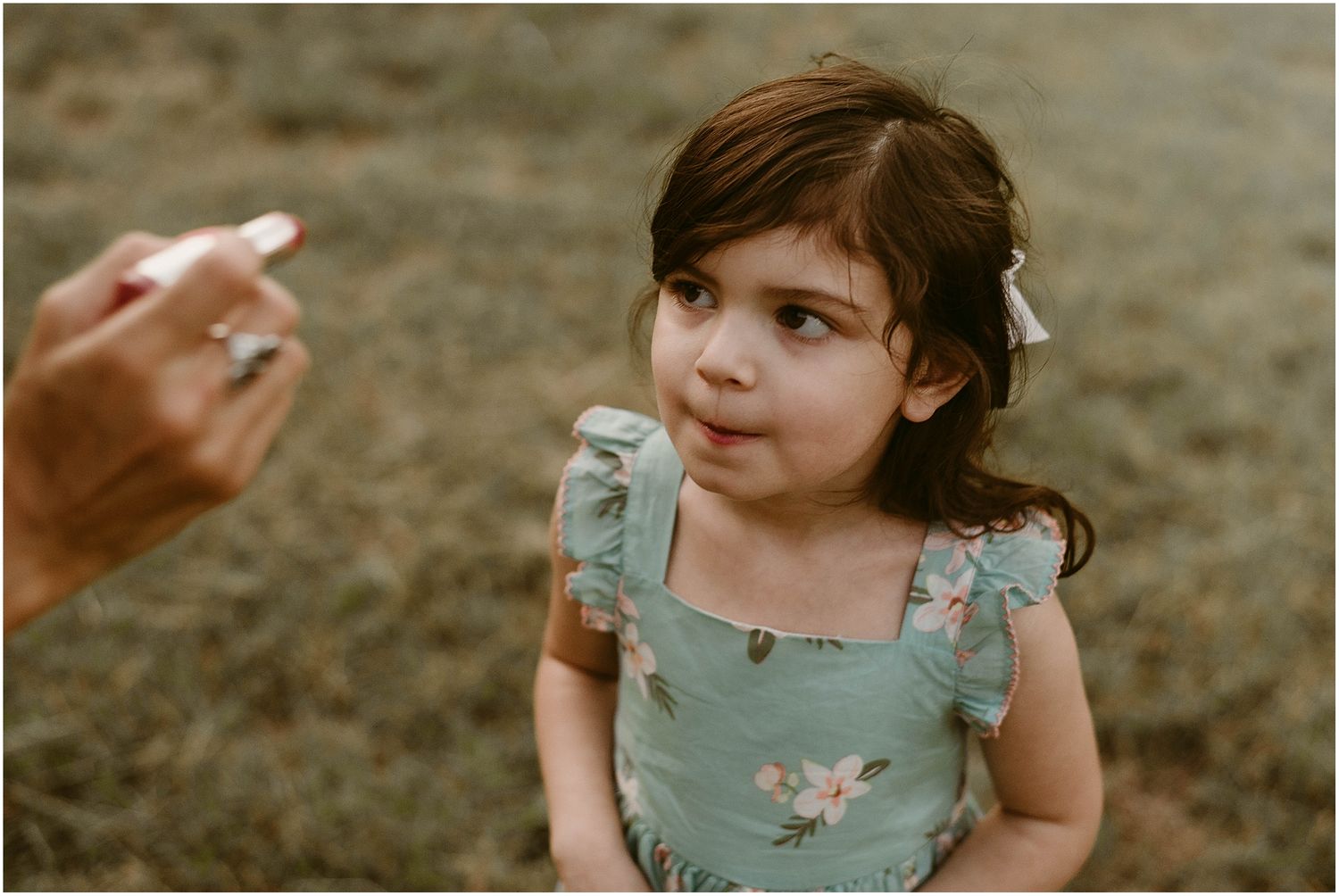 Close up portrait of child in mint floral dress during outdoor photo session.