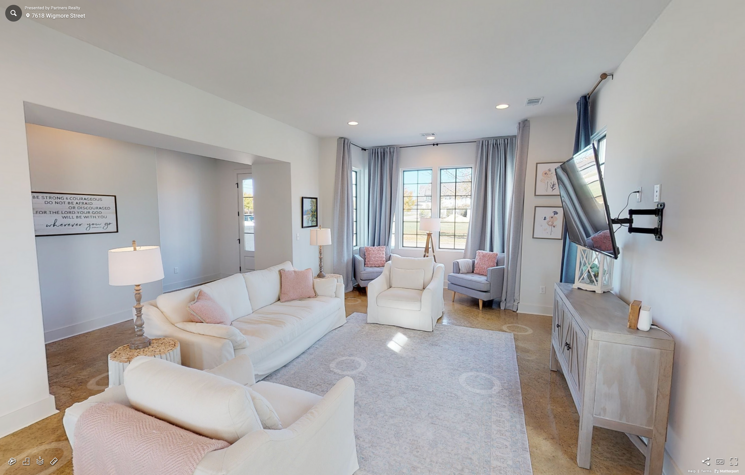 Bright living room with white furniture, gray walls, and natural light streaming through windows.