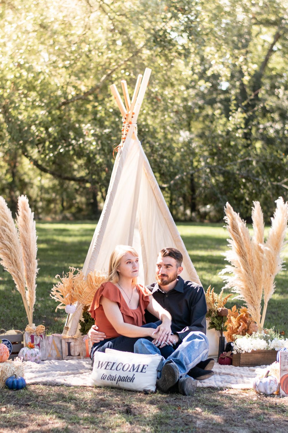 Cozy boho picnic setup with teepee, pampas grass, and welcome sign in a sunlit garden.