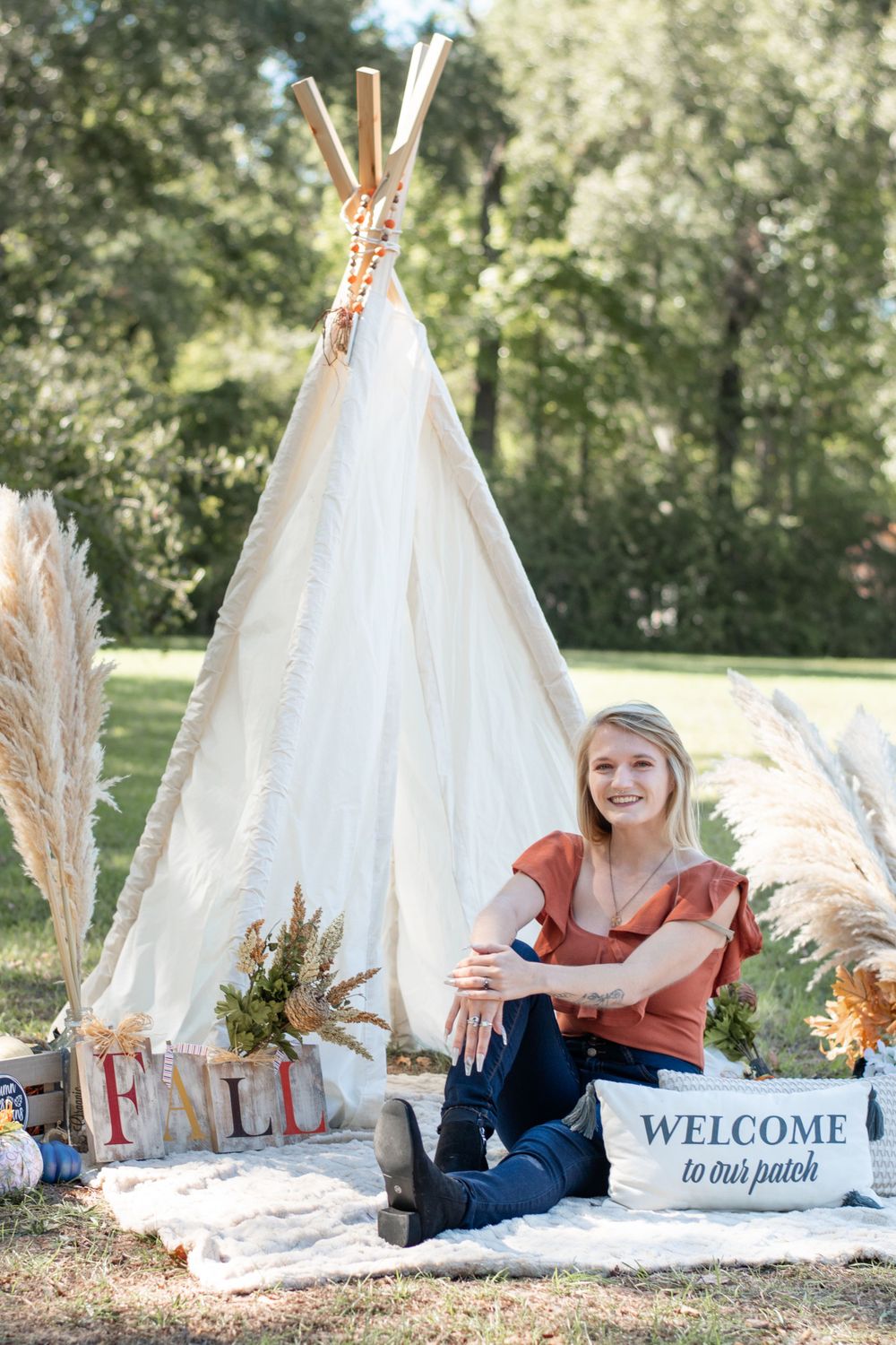 Boho-style teepee setup with pampas grass, welcome sign, and outdoor decor.
