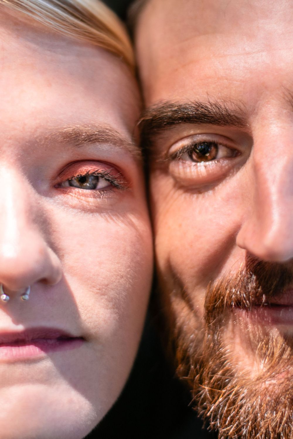 Extreme close-up portrait showing two faces side by side in warm sunlight.