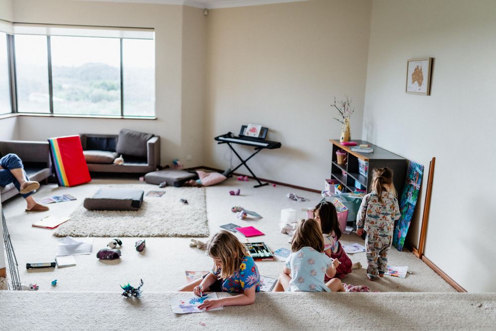 Cousins playing together in a lounge room, with toys all around them