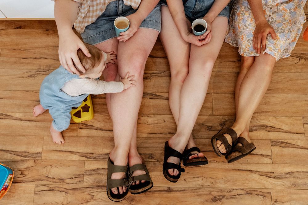 Legs of Sisters-in-law sitting together, with a toddler reaching over them