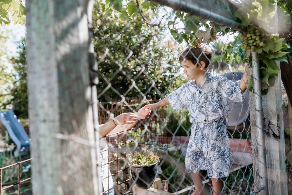 A young boy reaching towards him mum in their backyard in Perth