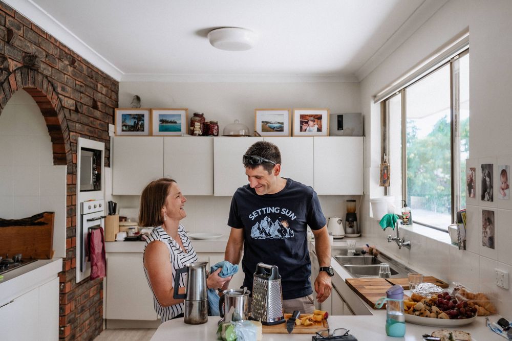 A husband and wife preparing food together in the kitchen, laughing