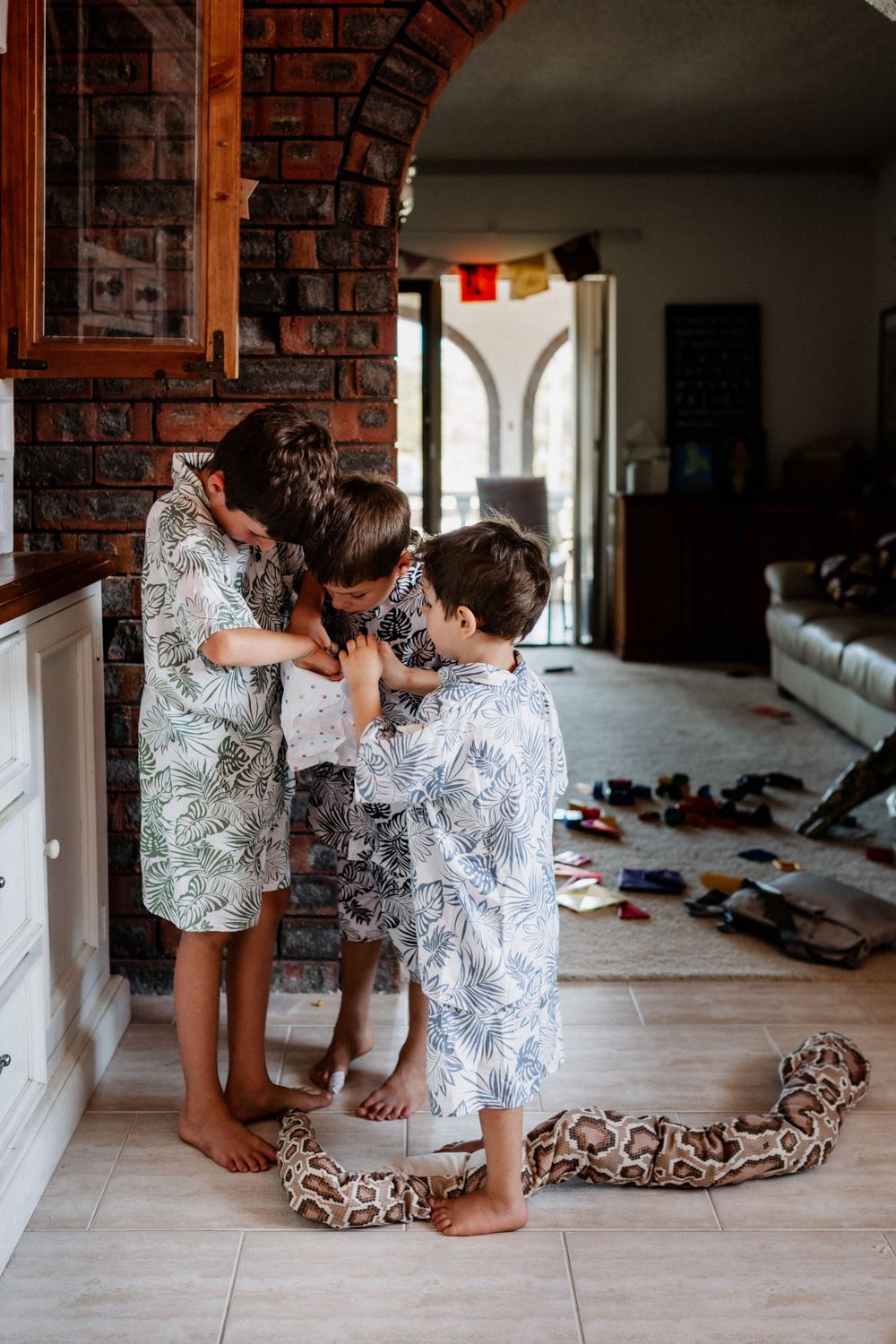 Three brothers looking in a bag of lollies together in their home