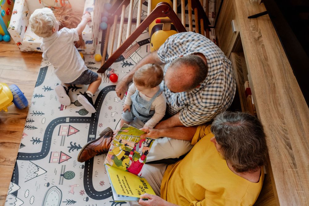 Grandparents at home with two grandchildren, reading and playing music together