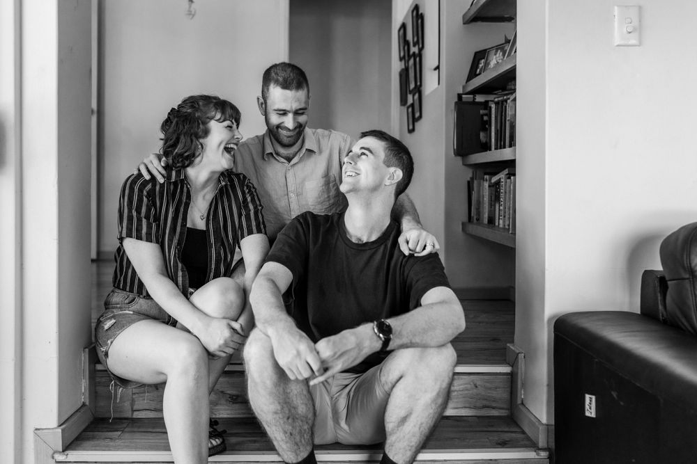 Three adult siblings in a home, laughing together