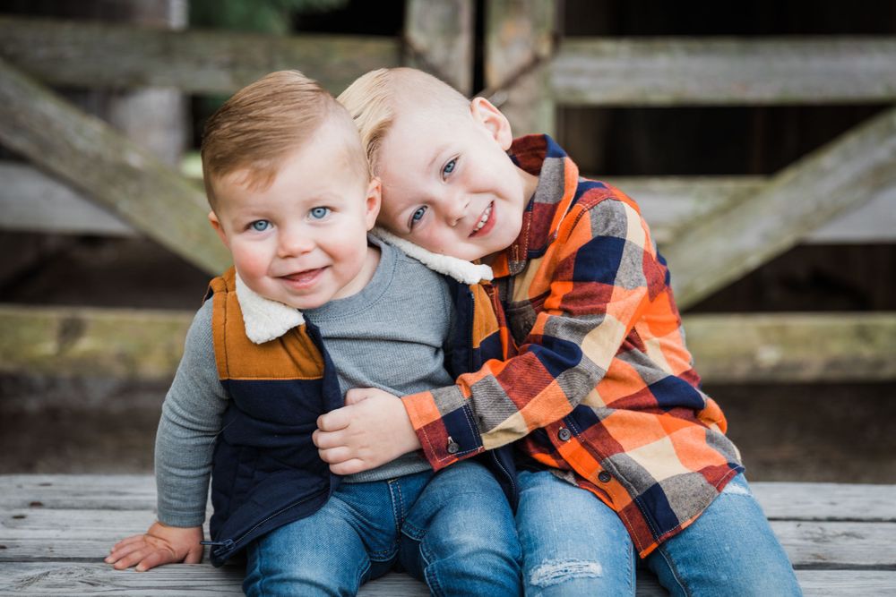 Two young siblings in casual clothes sharing a joyful moment on wooden deck.