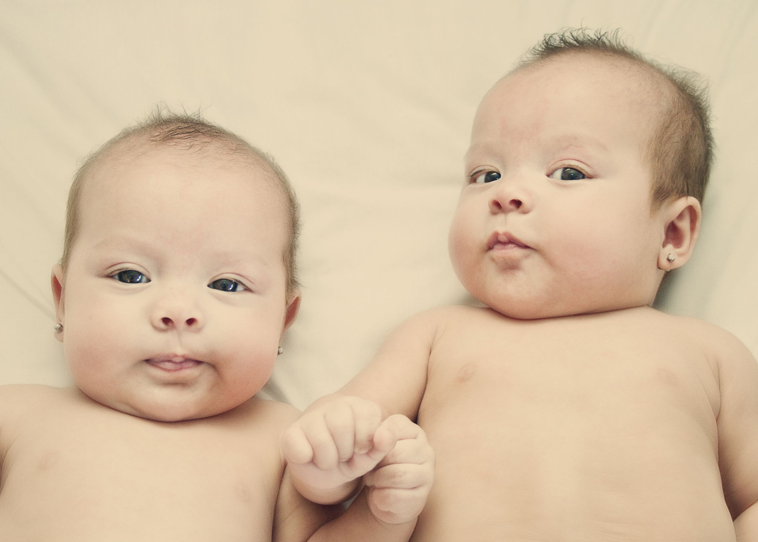 Collection of gentle close-up shots of an infant lying on cream-colored fabric.