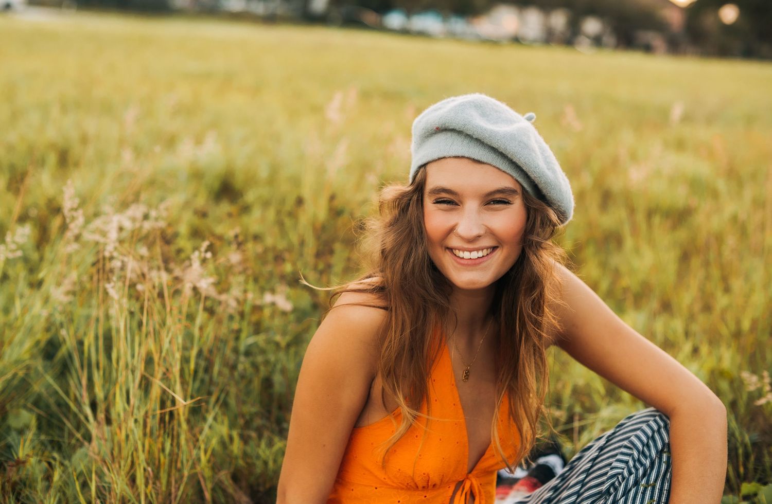 A summer picnic scene with a gray beret and orange tank top in a golden meadow.