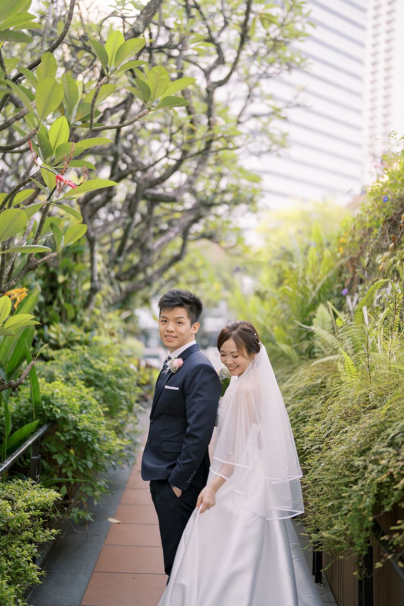Wedding couple shares intimate moment in lush rooftop garden setting.