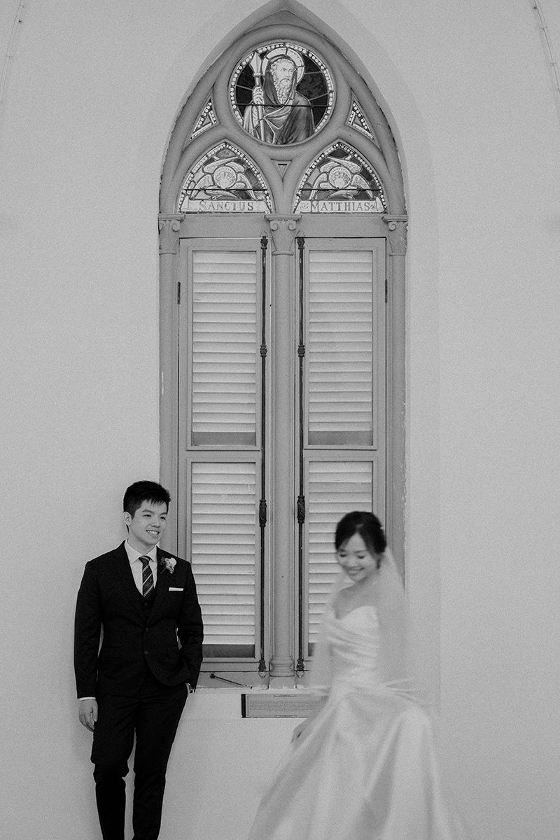 A black and white photo series showing a couple in formal attire posing by an arched church window.