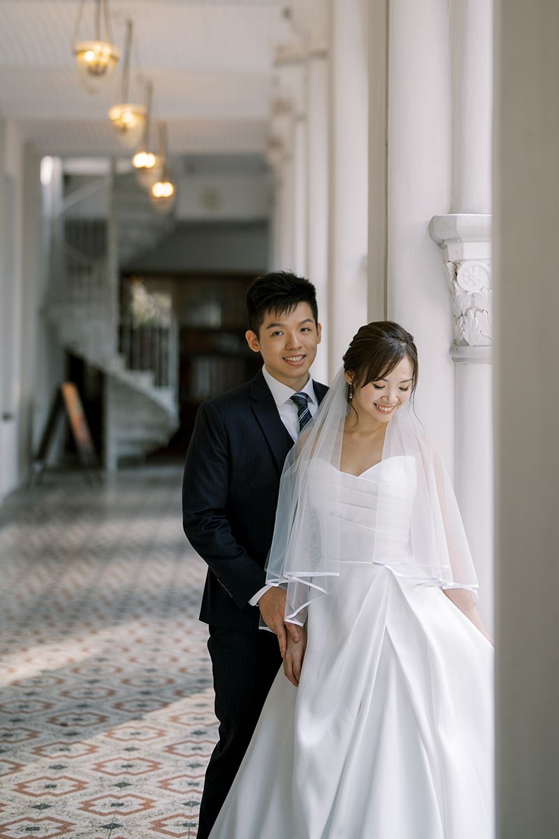 Wedding portraits taken in an elegant hallway with patterned floors and white columns.