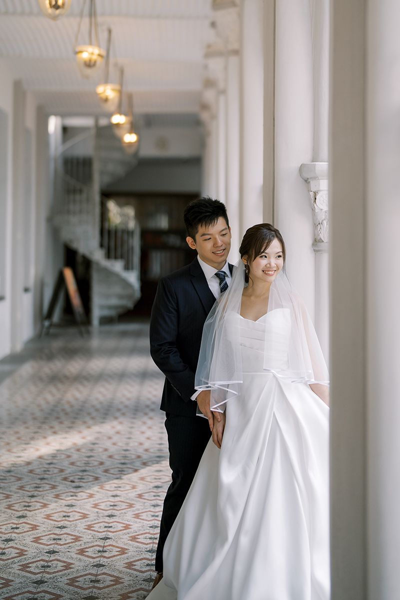 Elegant wedding portraits taken in a bright hallway with decorative floor tiles and columns.
