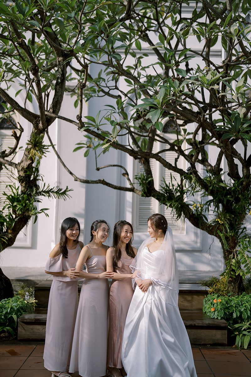 Wedding party photos under a tree with bridesmaids in matching dresses.