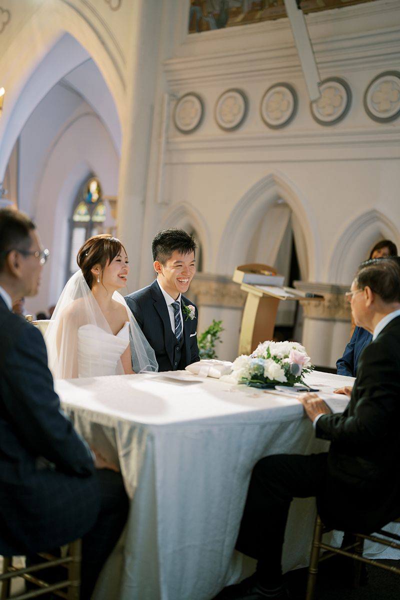 Wedding reception scene in an elegant white hall with classical architectural features.