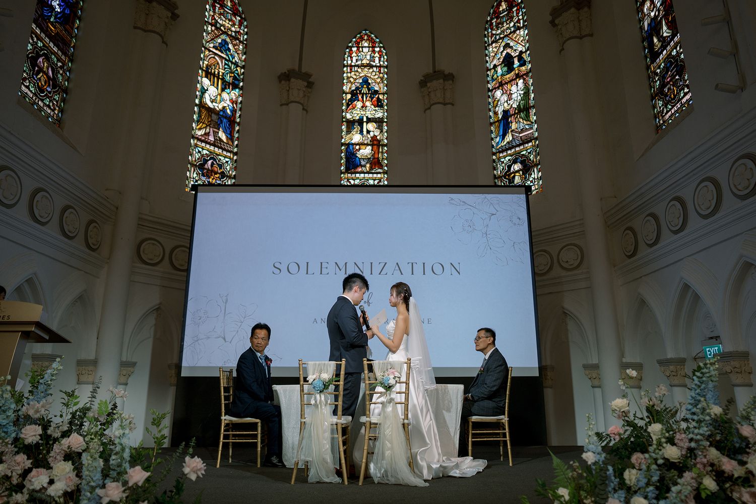 White church sanctuary decorated with floral arrangements and chandeliers for a wedding ceremony.