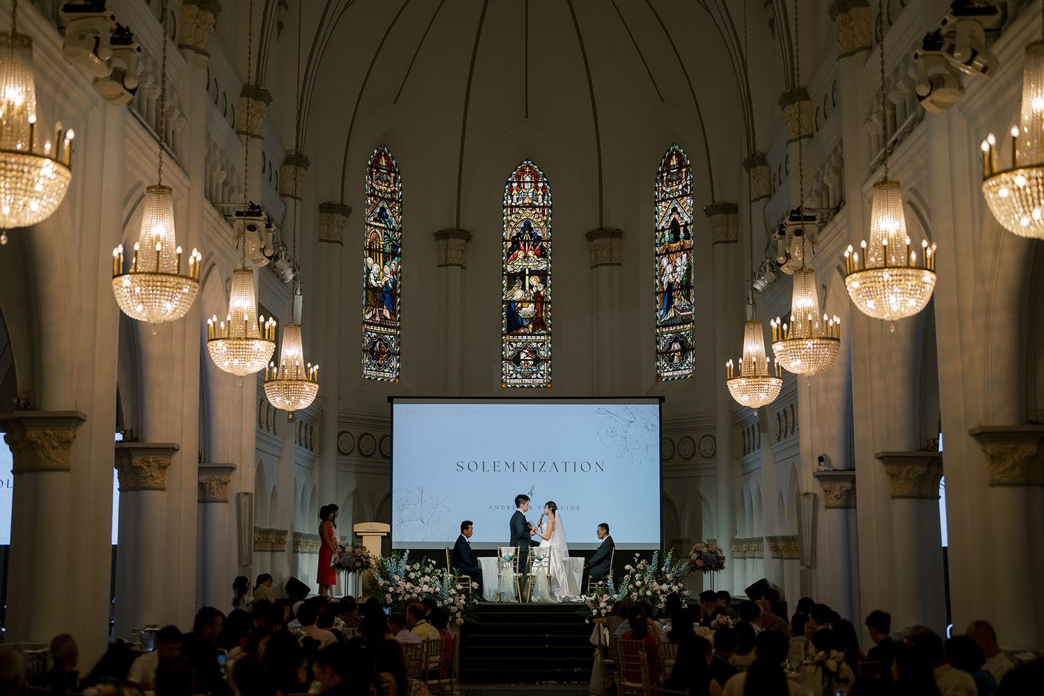 Panoramic view of a church wedding ceremony with elegant lighting and stained glass windows.