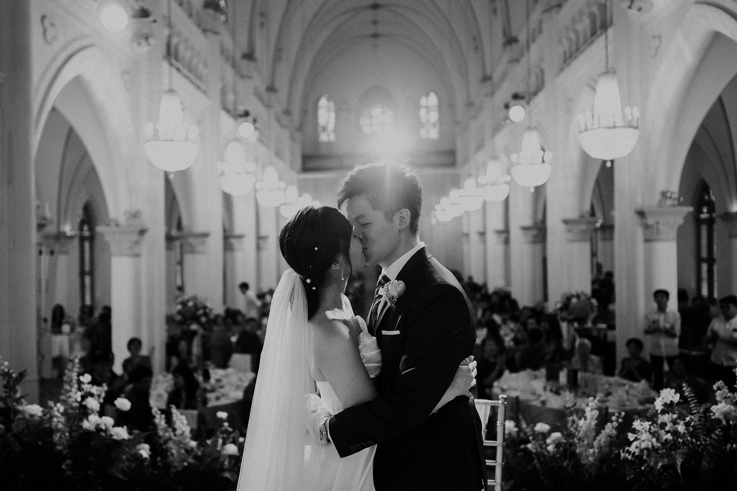 Black and white panorama of a wedding ceremony in a cathedral with dramatic lighting and architecture.