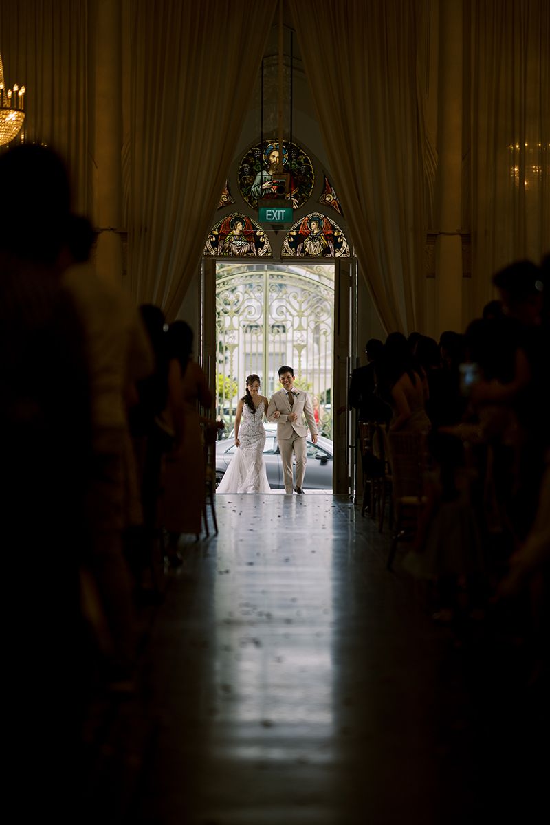 Silhouetted figures stand in an ornate doorway during a wedding ceremony.