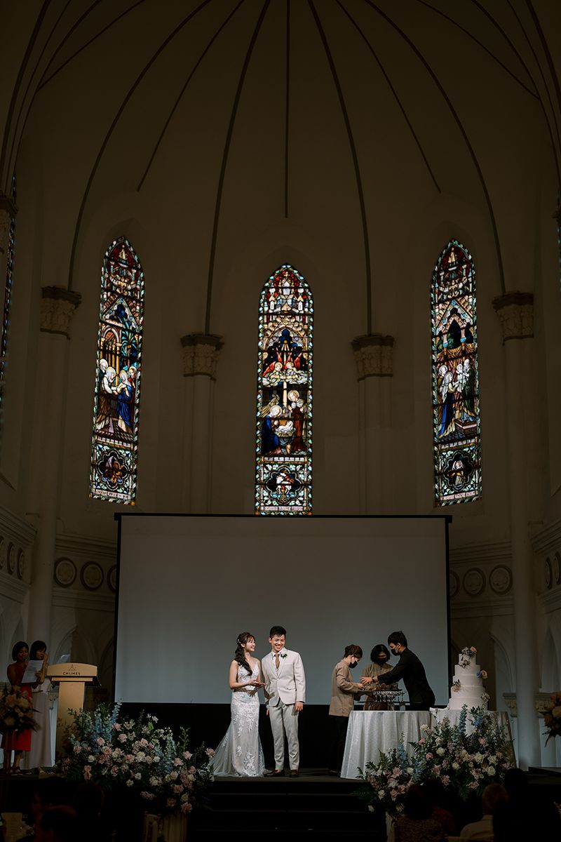 Wedding ceremony in a dramatic church setting with beautiful stained glass windows and dim lighting.