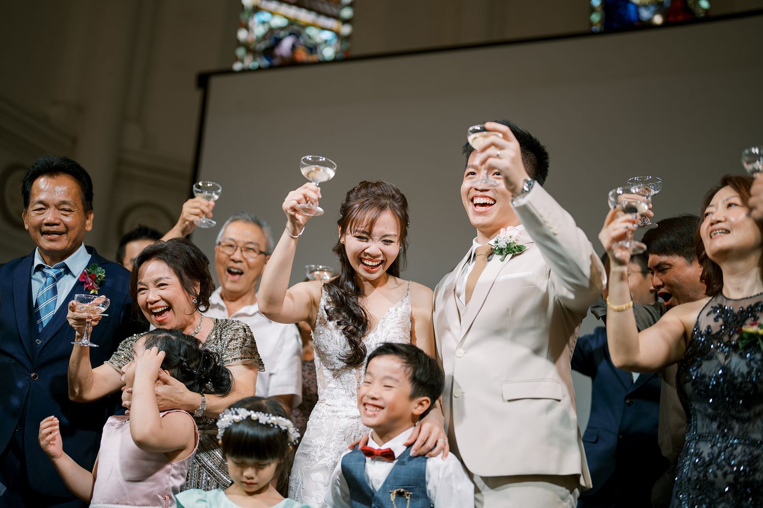 Wedding guests share joyful laughter and celebration during a festive reception moment.