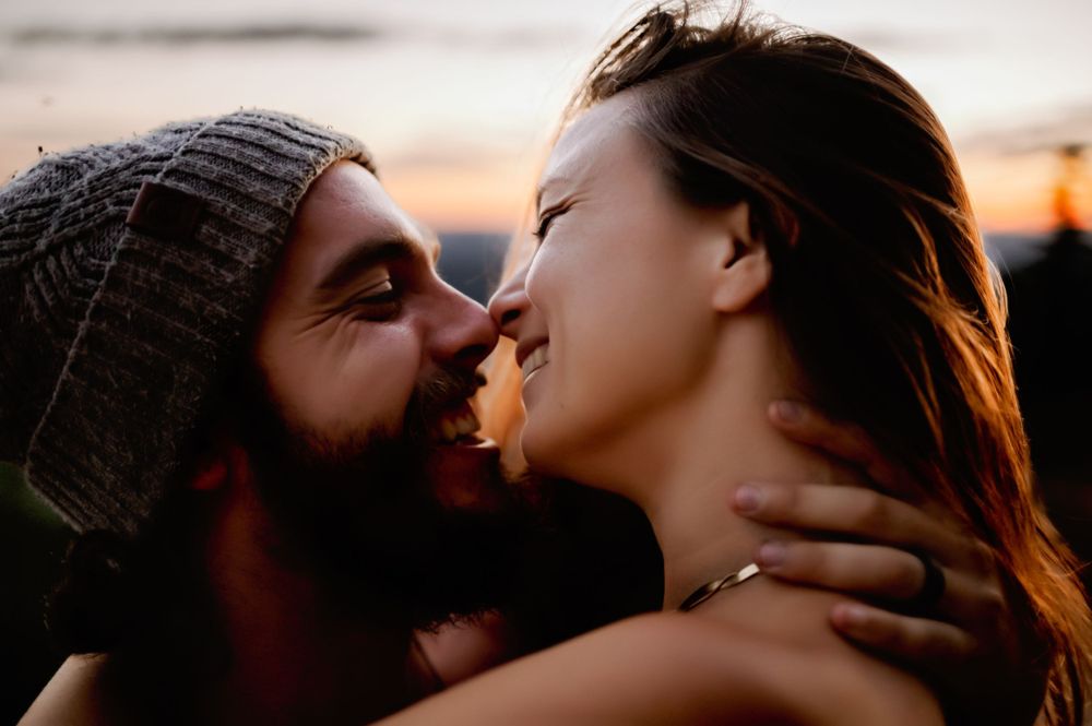 Close-up silhouettes of couple sharing intimate moment at sunset.
