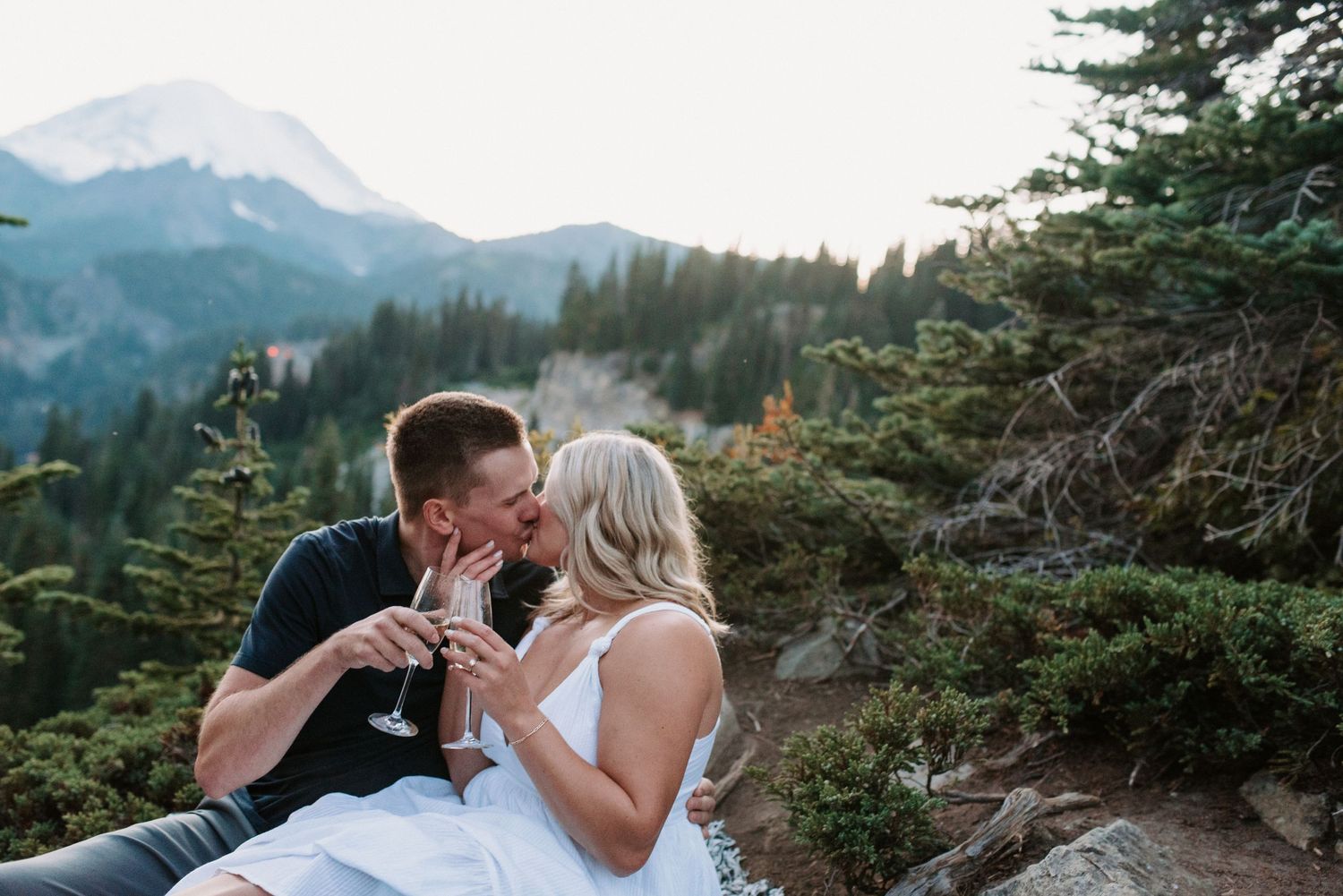 Scenic mountain engagement photos with evergreen trees and dramatic landscape views.