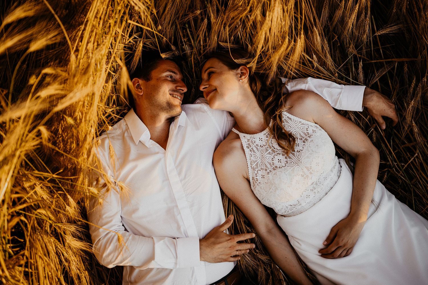 Hochzeitspaar liegt in einem Kornfeld bei Jena und schaut sich an.