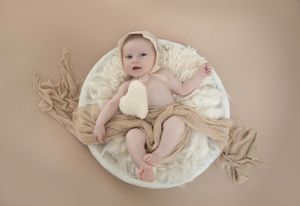 Newborn Photo little girl wooden bowl, cream flokati, cream vintage lace bonnet,  beige accessories holding cream heart