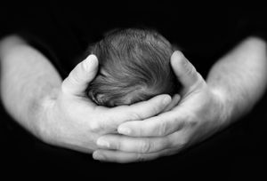 Black & White Newborn photo/image Daddy cradling babies head safely in his hands.