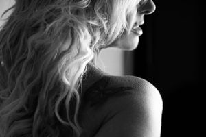 Black & White Portrait blonde female Boudoir Shoot, butterfly tattoo on shoulder, model lip stud piercing