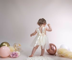 child portrait, cream backdrop rose gold, pink, cream balloons, pink flowers child wearing cream lace ribboned dress