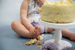 Cake smash, close up child foot image, broken cake on white cake stand
