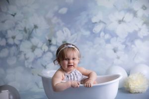 child photography white bath, blue floral backdrop cream and grey and white balloons and flowers