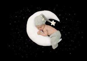 Newborn Photoshoot image of baby on moon, wearing grey sleepy hat with white star bobble and matching grey knitted pants