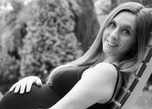 Black & White Maternity Portrait of beautiful Mum to Be hand on bump smiling at camera, garden backdrop